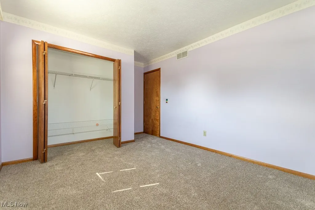 Unfurnished bedroom with light carpet, a closet, and a textured ceiling