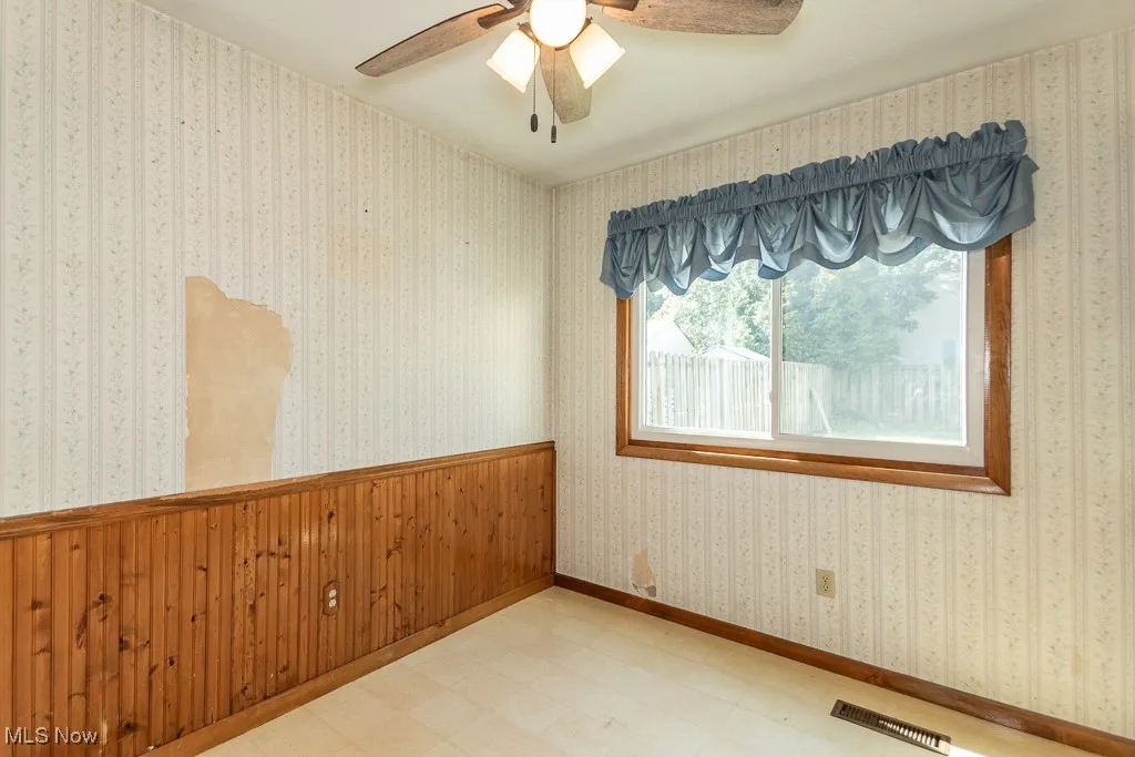 Dining room with tile patterned floors, a ceiling fan, and wallpapered walls