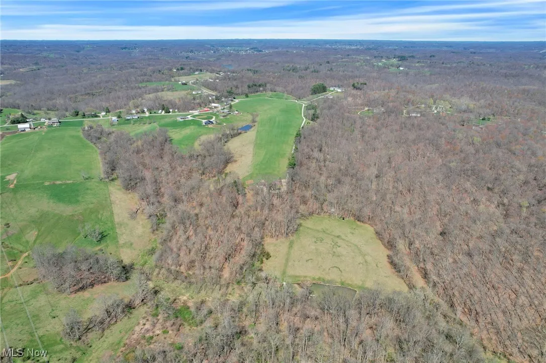 Aerial overview of property's location with a heavily wooded area and a golf club