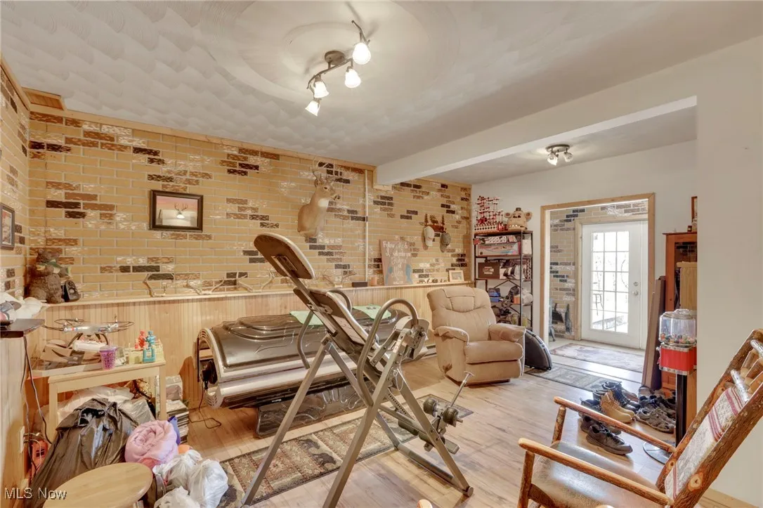 Office featuring brick wall, light wood finished floors, and beam ceiling