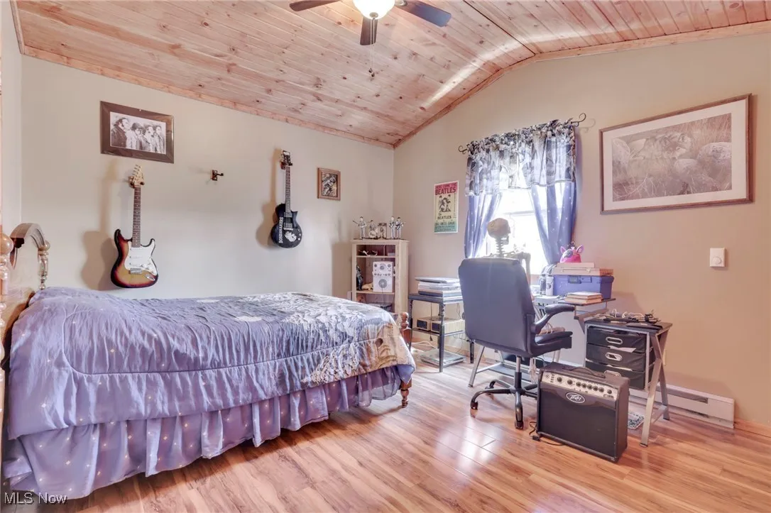 Bedroom featuring wood ceiling, vaulted ceiling, wood finished floors, ceiling fan, and baseboard heating
