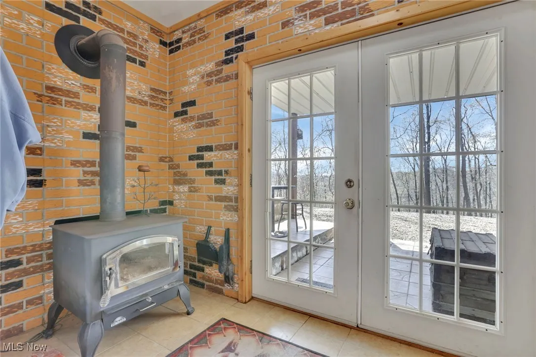 Doorway with a wood stove, brick wall, and light tile patterned floors