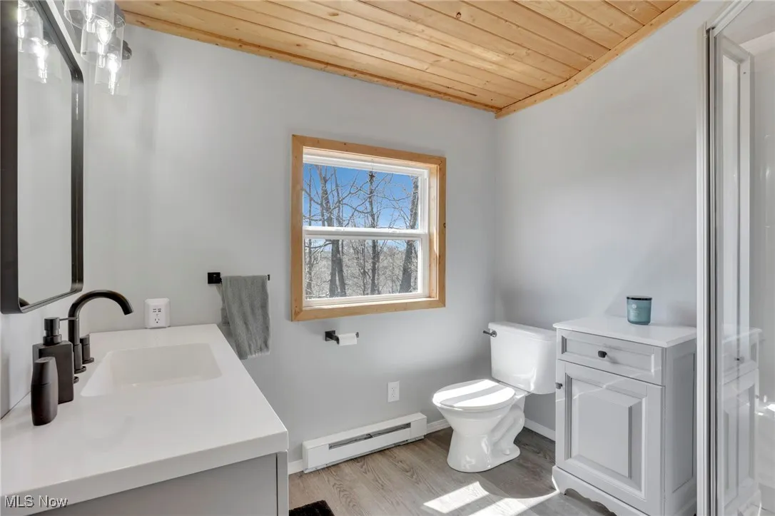 Full bath with a baseboard heating unit, vanity, wood ceiling, wood finished floors, and a shower with door