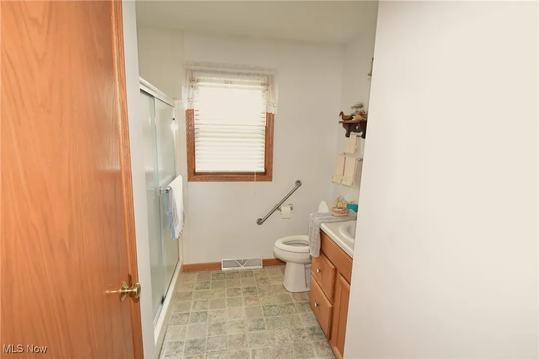 Full bathroom featuring vanity, a shower with door, and stone finish floors