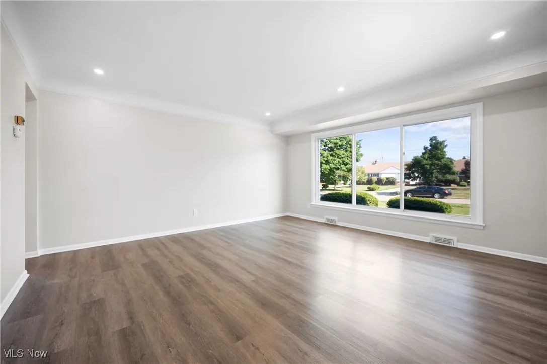 Living room featuring dark wood-style floors, crown molding, and recessed lighting