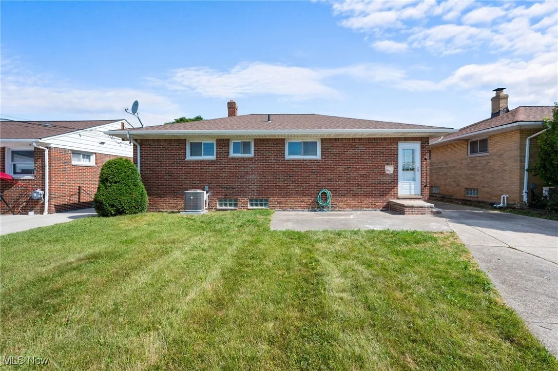 Back of property featuring brick siding, a lawn, and a chimney