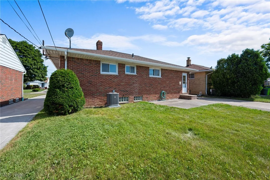 Back of property with a chimney, brick siding, and a lawn