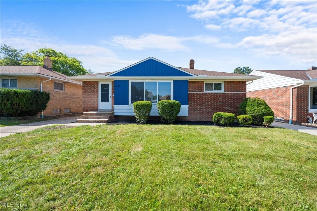 View of front of home with a front yard, entry steps, brick siding, and a chimney