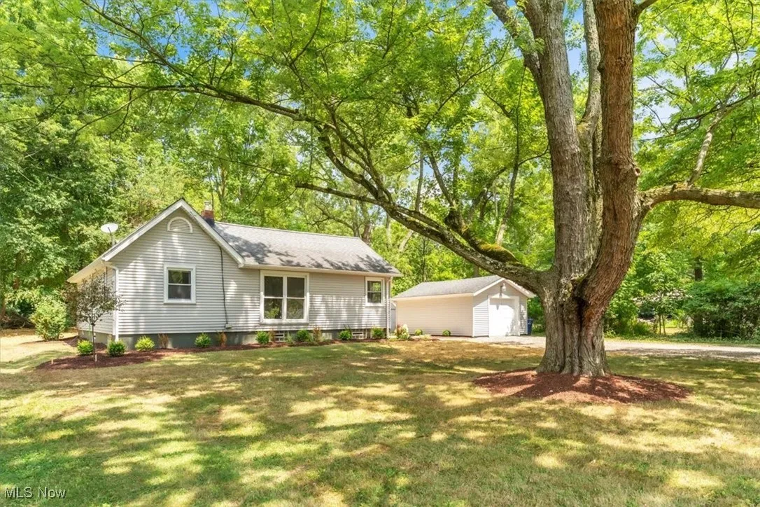 Single story home with an outbuilding, a chimney, a detached garage, and a front lawn