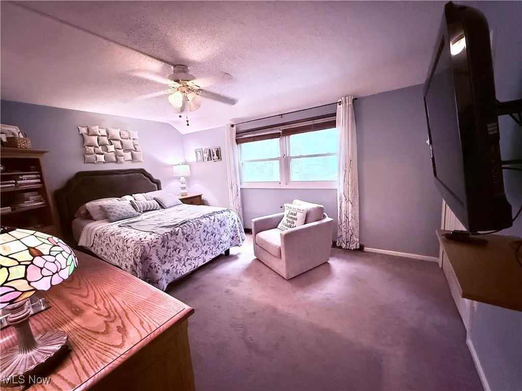Bedroom featuring a textured ceiling, carpet floors, and ceiling fan