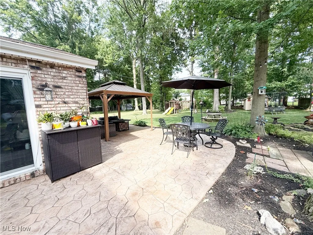 View of patio featuring a playground, a gazebo, and an outdoor living space