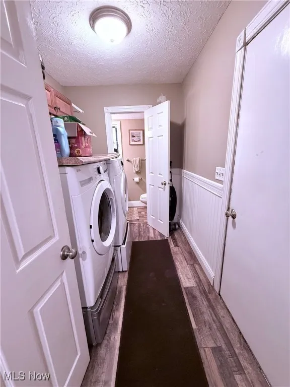 Laundry area featuring washer and clothes dryer, wainscoting, dark wood finished floors, and a textured ceiling