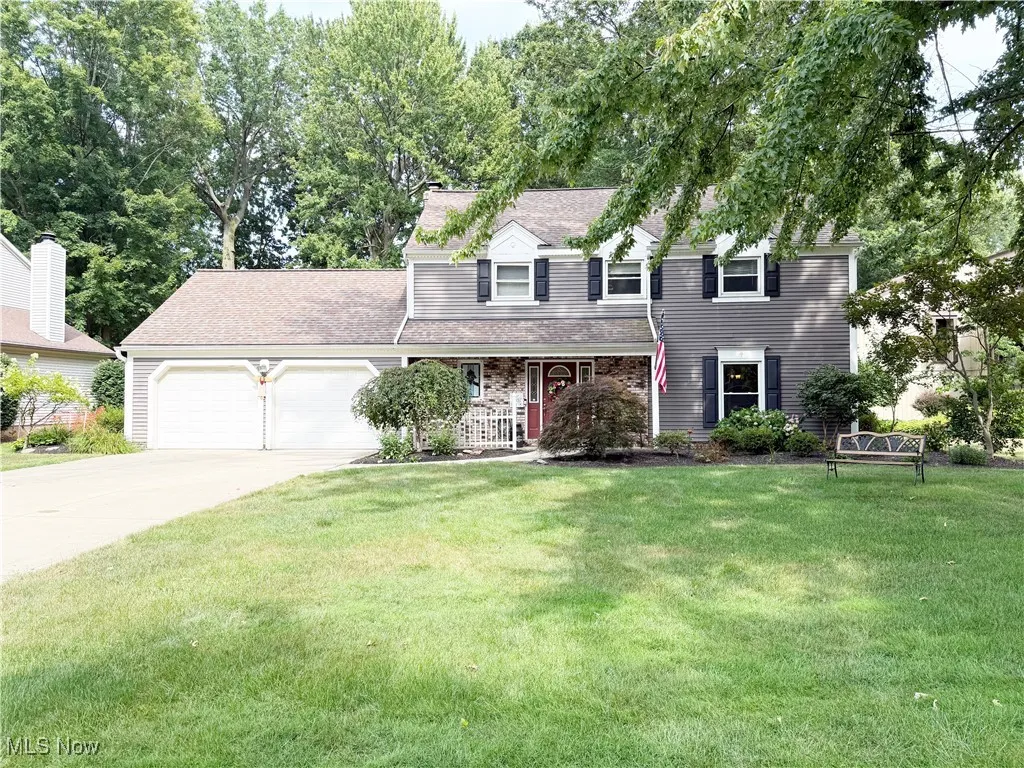 Traditional-style house featuring a porch, driveway, a front lawn, a garage, and a shingled roof