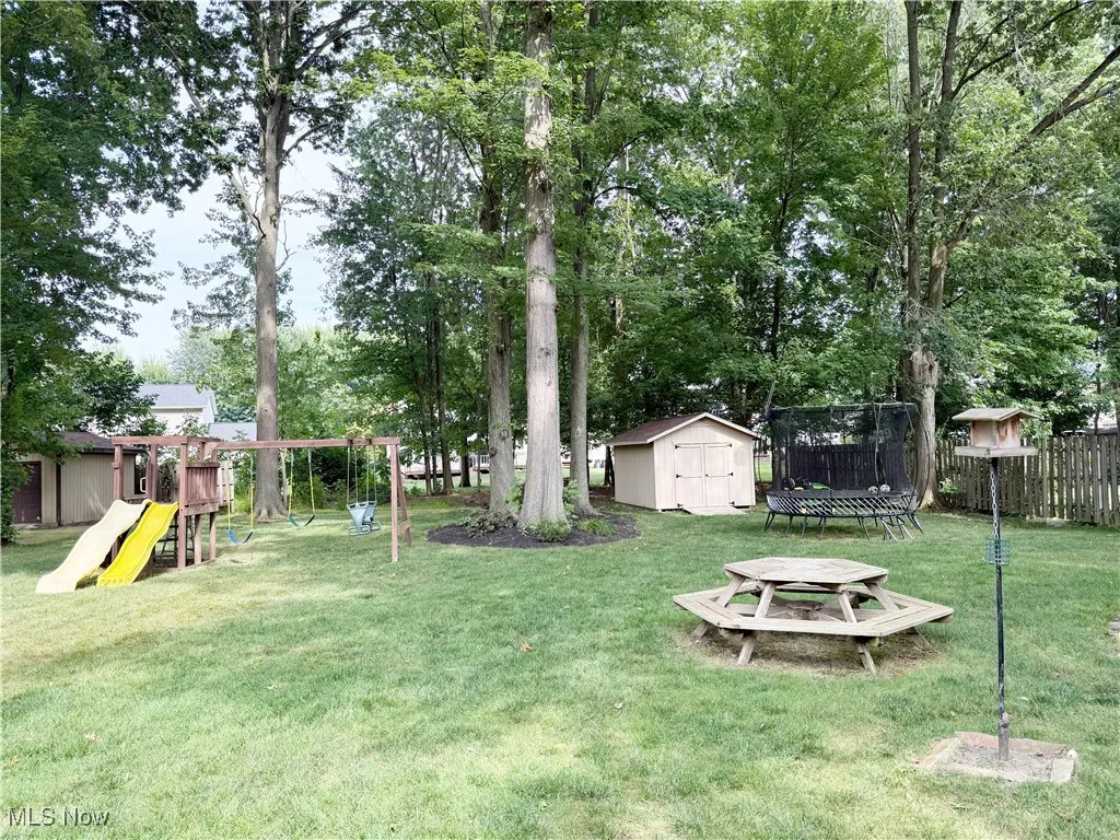 View of yard with a playground, a storage unit, and a trampoline