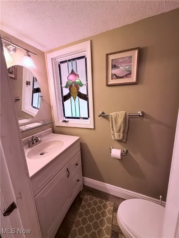 Half bath with vanity and a textured ceiling