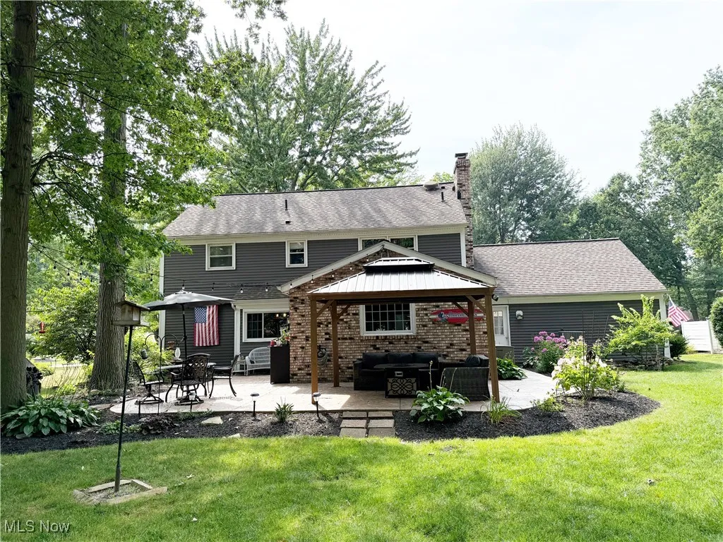Rear view of house featuring a gazebo, outdoor lounge area, brick siding, a chimney, and a patio area