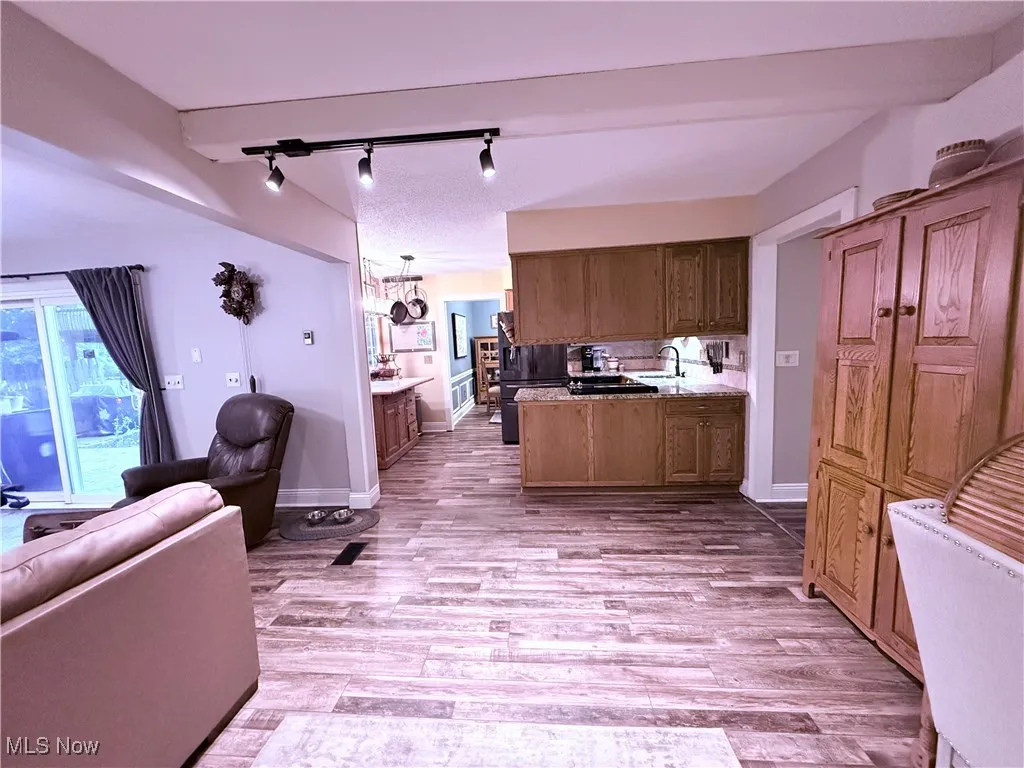 Kitchen with light wood-style floors, track lighting, open floor plan, light countertops, and freestanding refrigerator