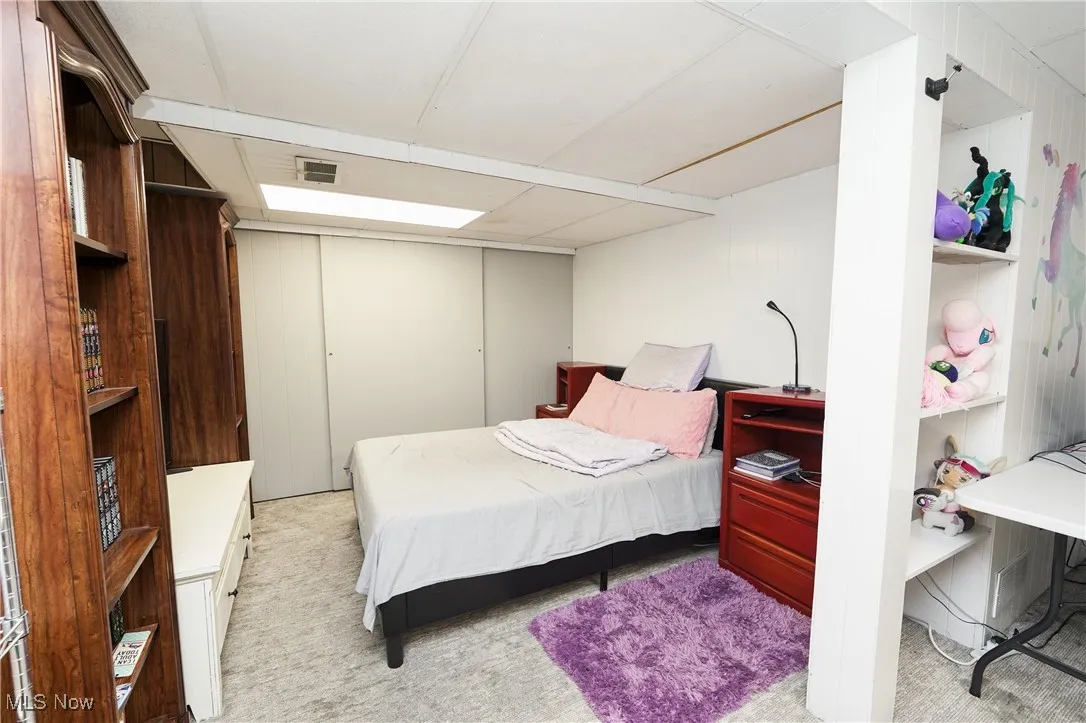 Bedroom with light colored carpet and a closet