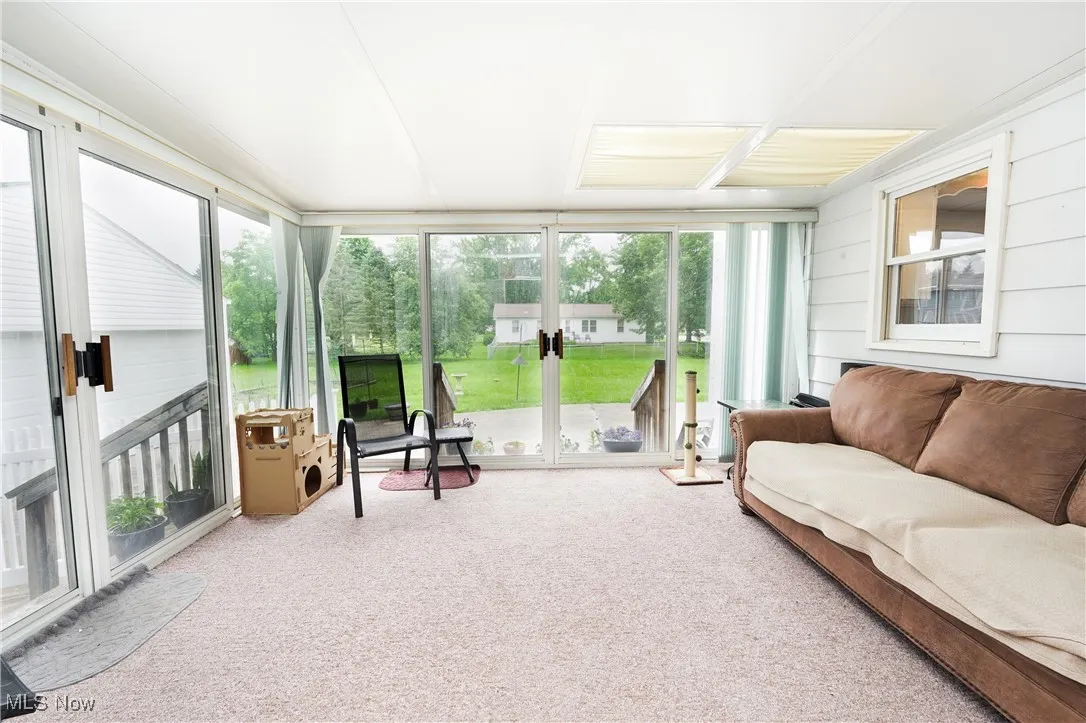 Sunroom / solarium featuring carpet floors, a wall of windows, and wooden walls