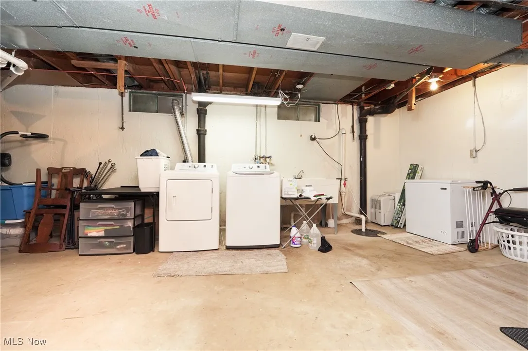 Unfinished below grade area with washer and dryer and fridge