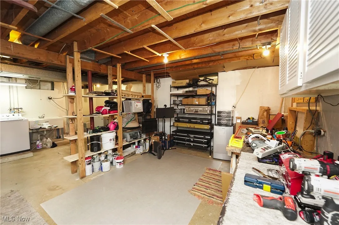 Unfinished basement with washer / dryer and fridge