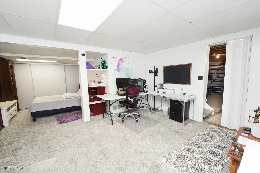 Home office with a paneled ceiling and light colored carpet