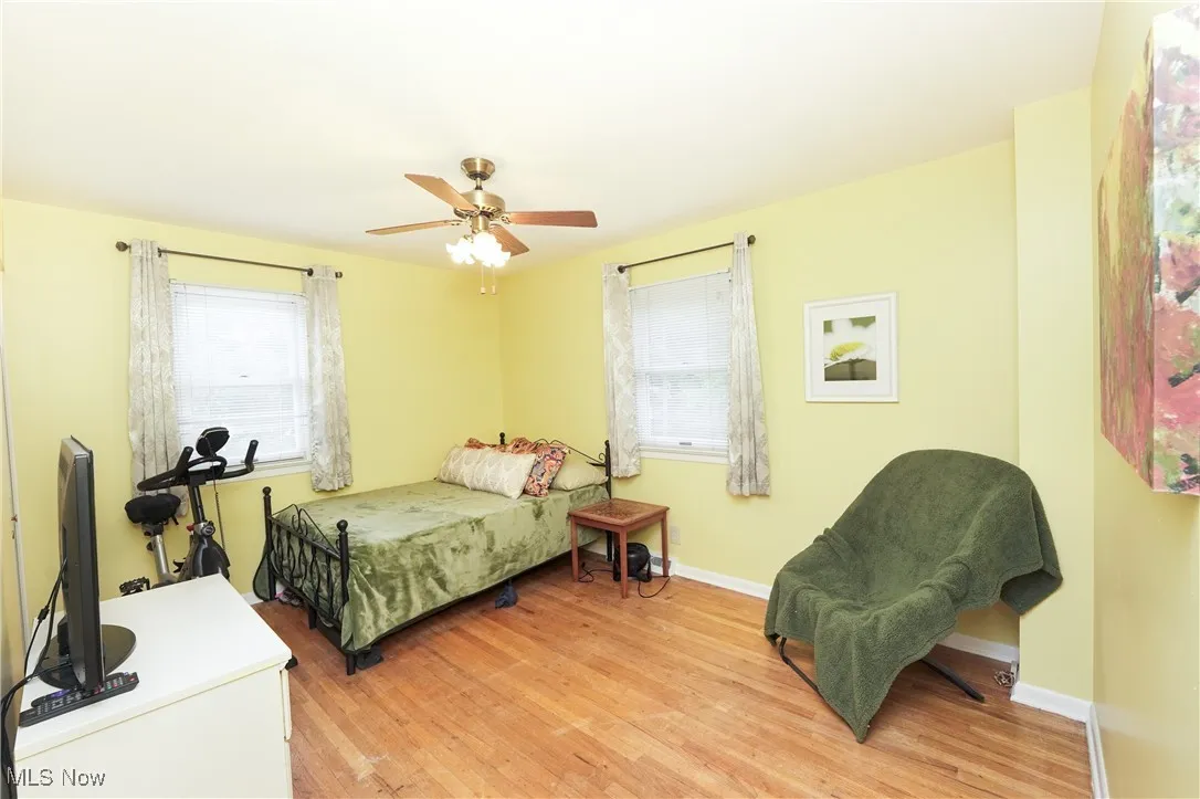 Bedroom with light wood-style flooring, multiple windows, and ceiling fan