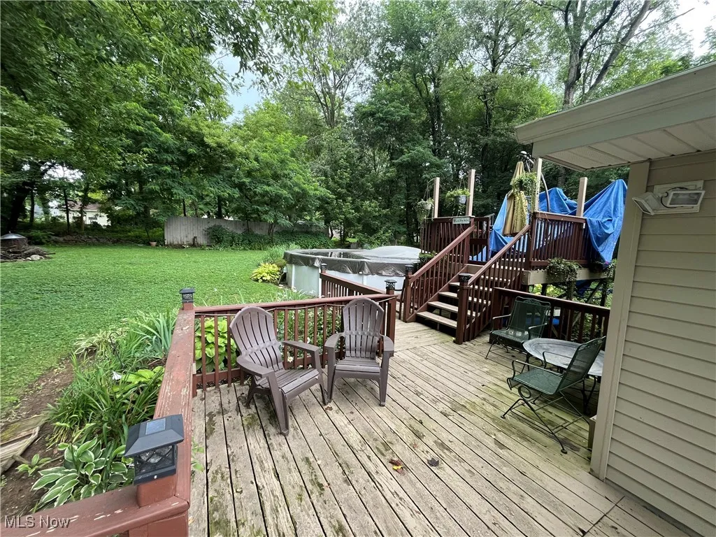 Deck with a hot tub and a lawn