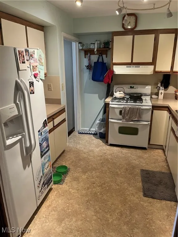Kitchen with range, fridge, light countertops, and white cabinets