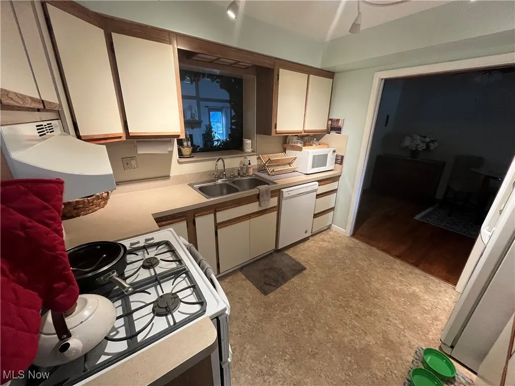 Kitchen with light countertops, white appliances, white cabinetry, and exhaust hood