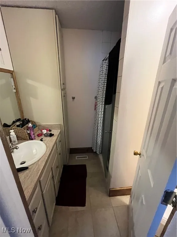 Bathroom featuring vanity, a shower stall, and tile patterned floors