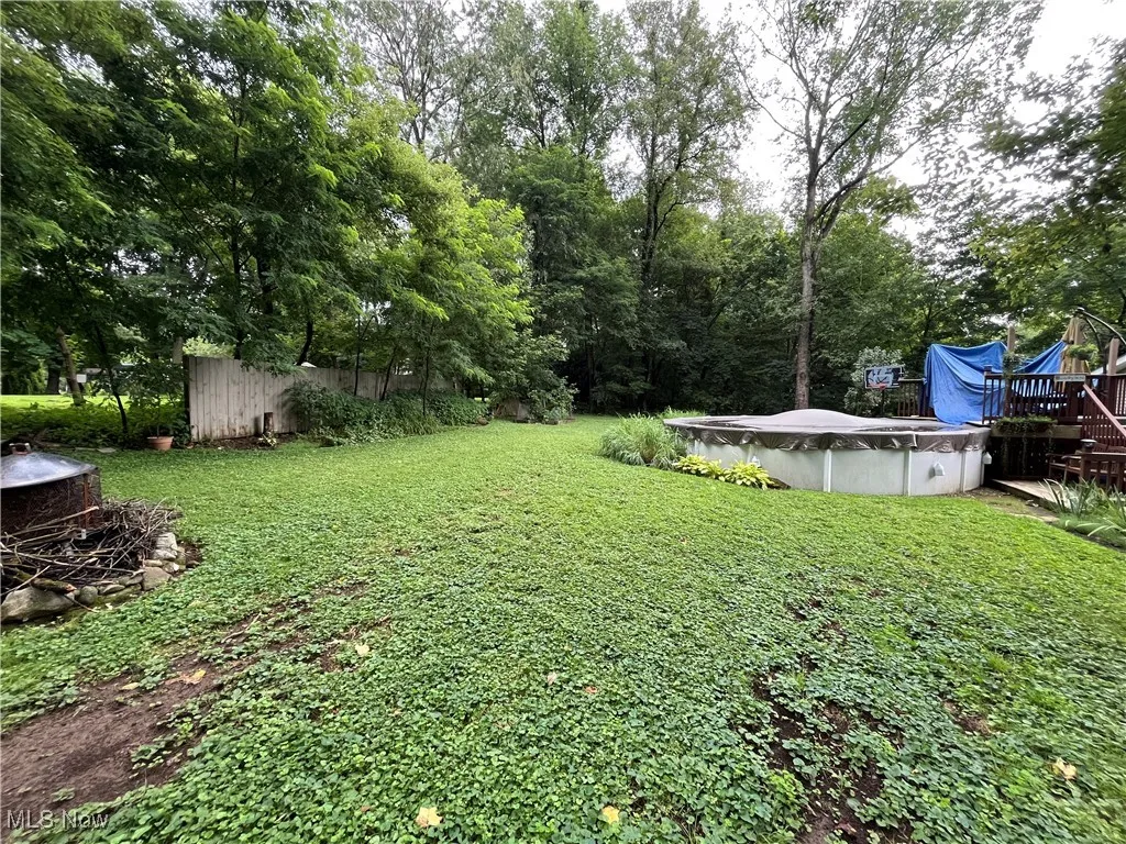 View of yard with a covered pool, a deck, and view of wooded area
