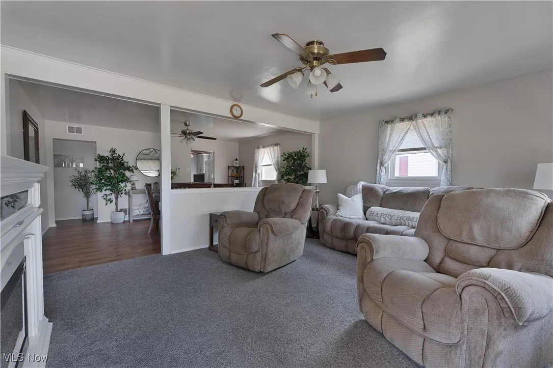 Carpeted living area with a fireplace and ceiling fan