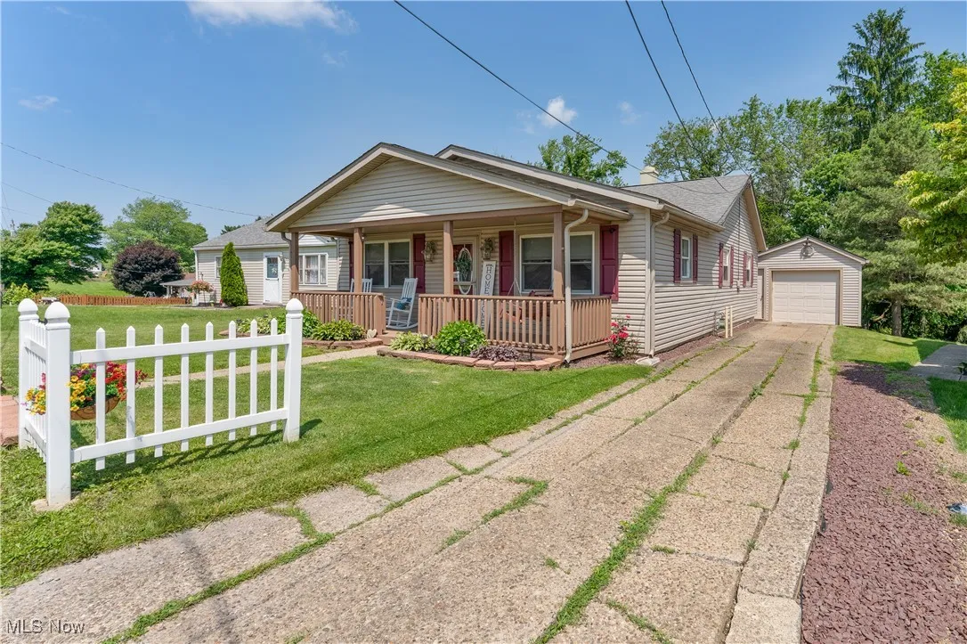 View of front of property with driveway, a porch, an outbuilding, and a garage