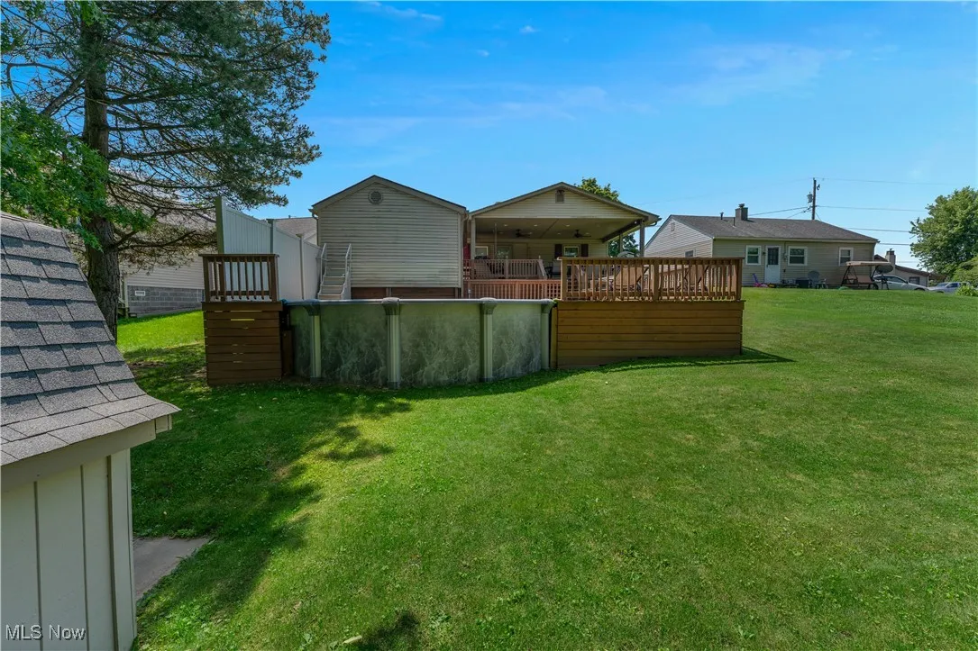 View of green lawn featuring a wooden deck and an outdoor pool