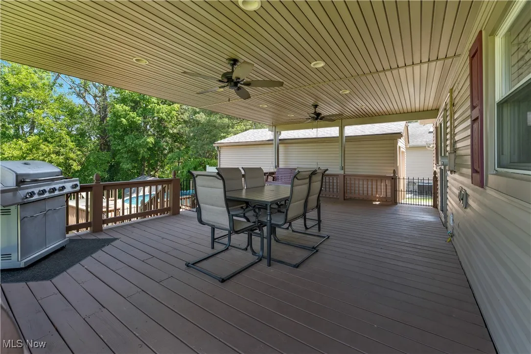 Wooden deck featuring area for grilling, outdoor dining space, and ceiling fan