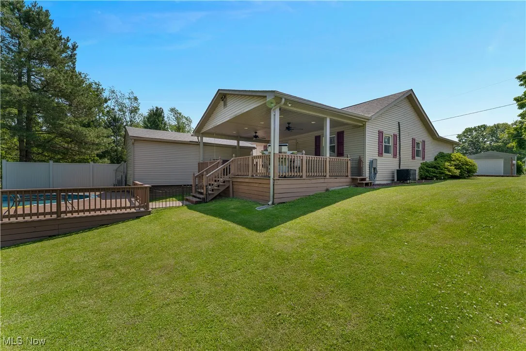 Rear view of property with a ceiling fan, a deck, a fenced backyard, a garage, and stairway