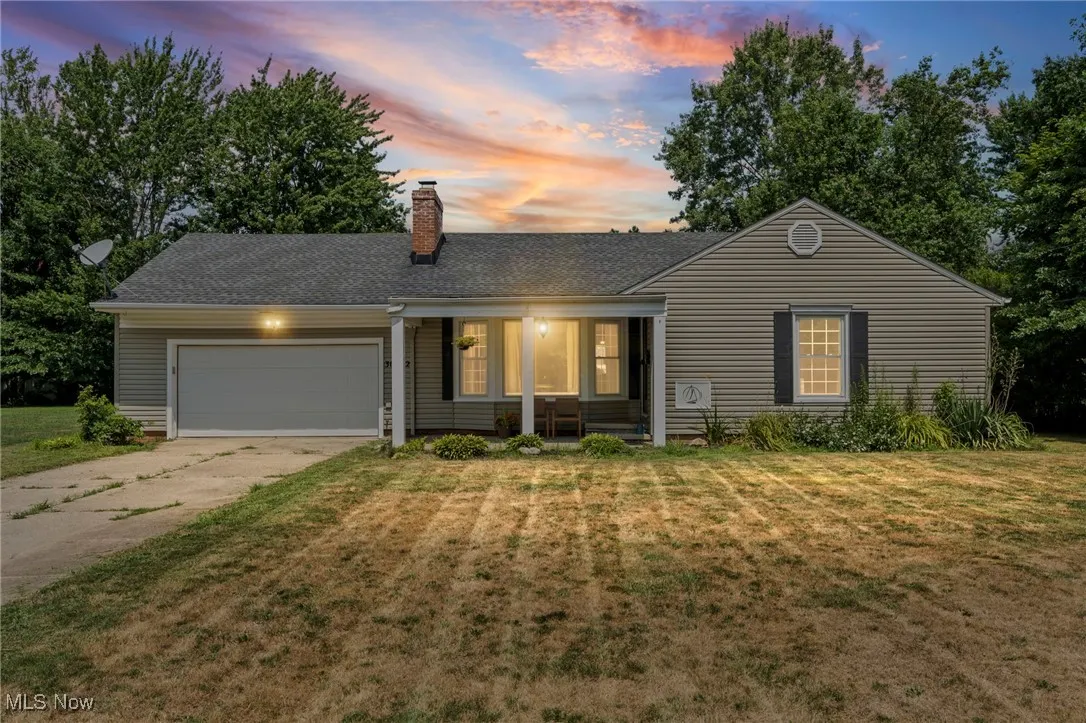 Ranch-style house featuring a garage, driveway, a lawn, a chimney, and roof with shingles