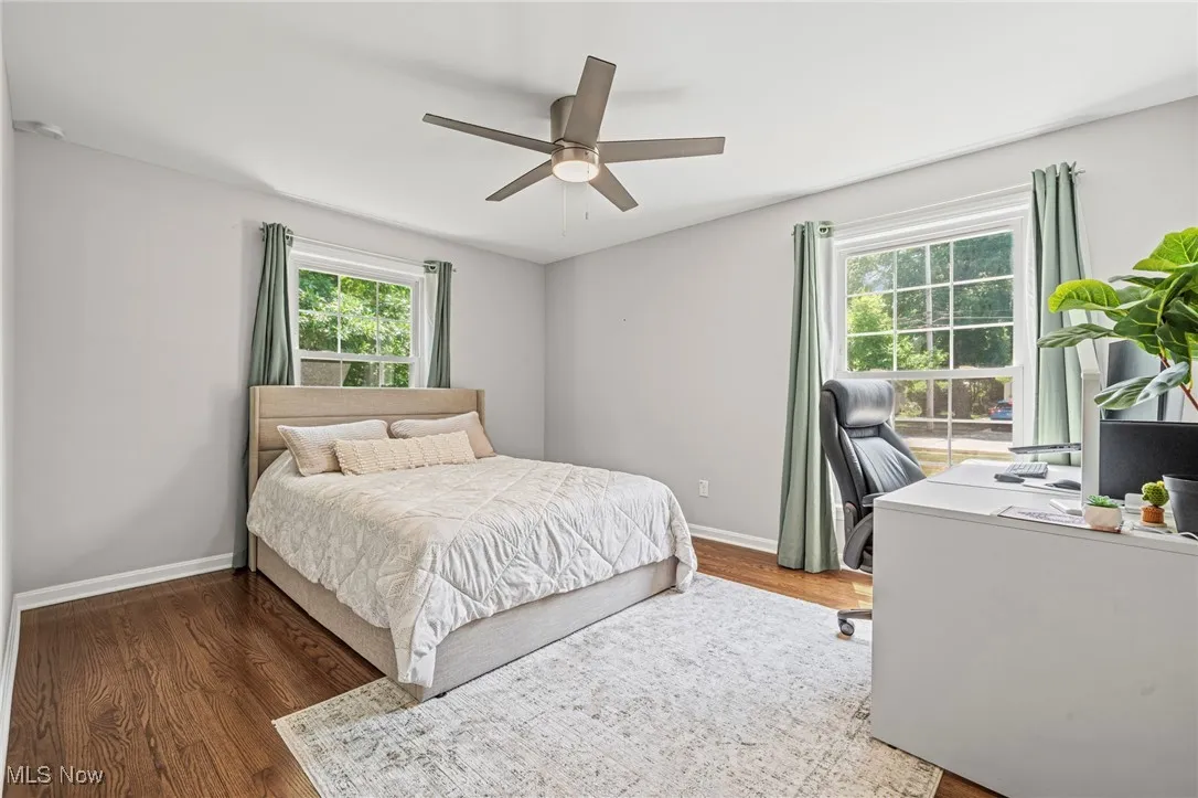 Bedroom featuring wood finished floors, an office area, and a ceiling fan