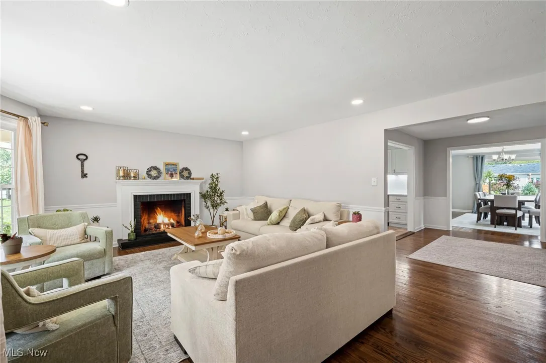 Living room with plenty of natural light, dark wood-style flooring, a lit fireplace, recessed lighting, and a chandelier