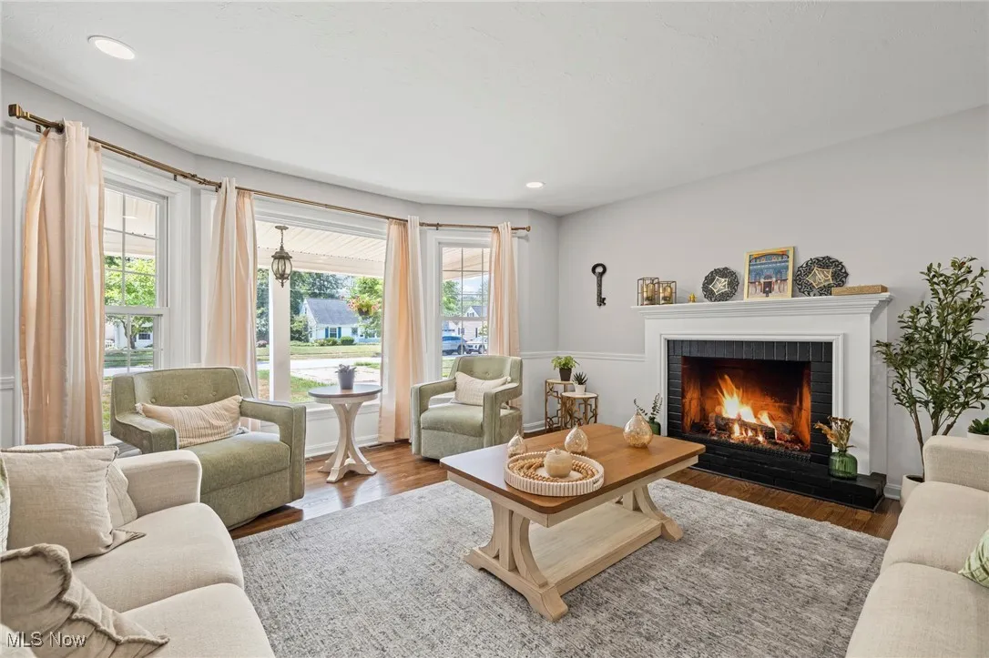 Living room with plenty of natural light, a tiled fireplace, wood finished floors, and recessed lighting