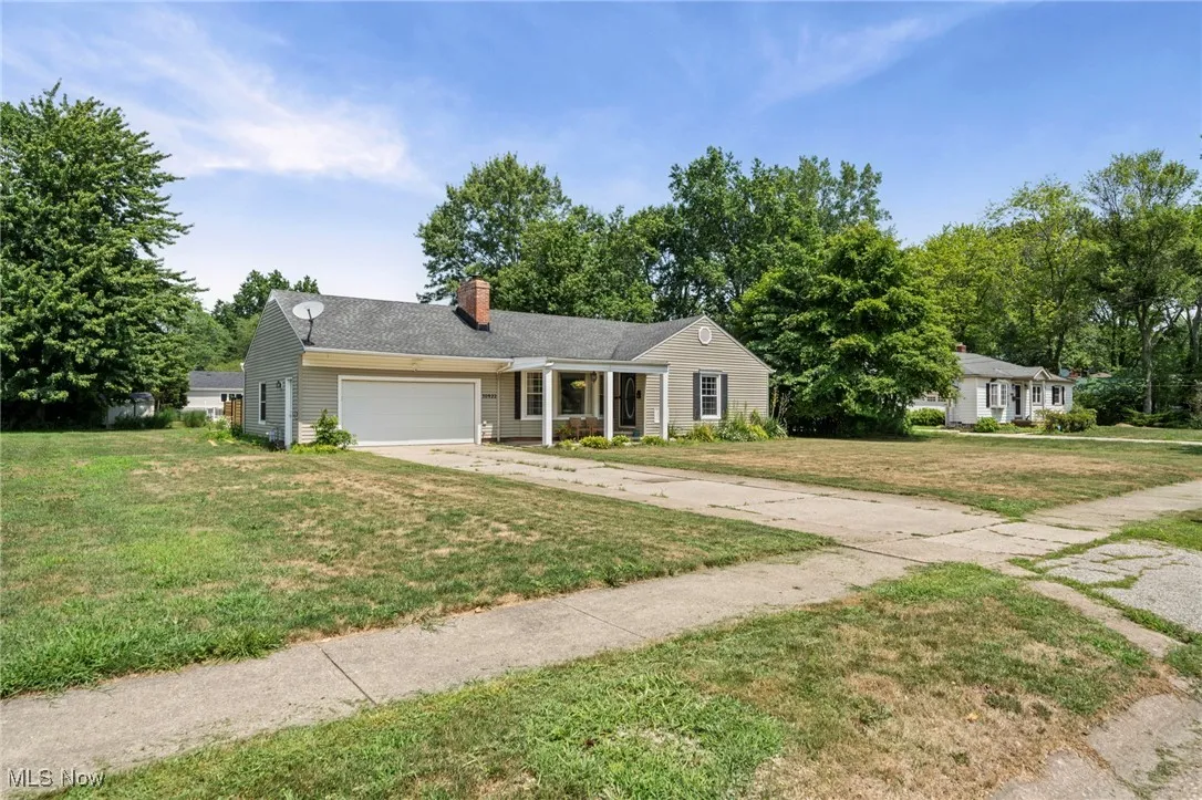 Ranch-style house with driveway, a chimney, a front lawn, and a garage