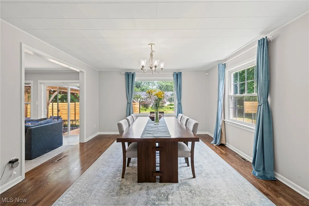 Dining space featuring healthy amount of natural light, a chandelier, wood finished floors, and crown molding