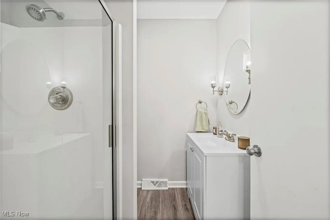 Bathroom featuring a stall shower, vanity, and wood finished floors