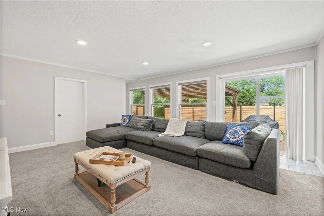 Living room featuring ornamental molding, recessed lighting, carpet flooring, and a textured ceiling