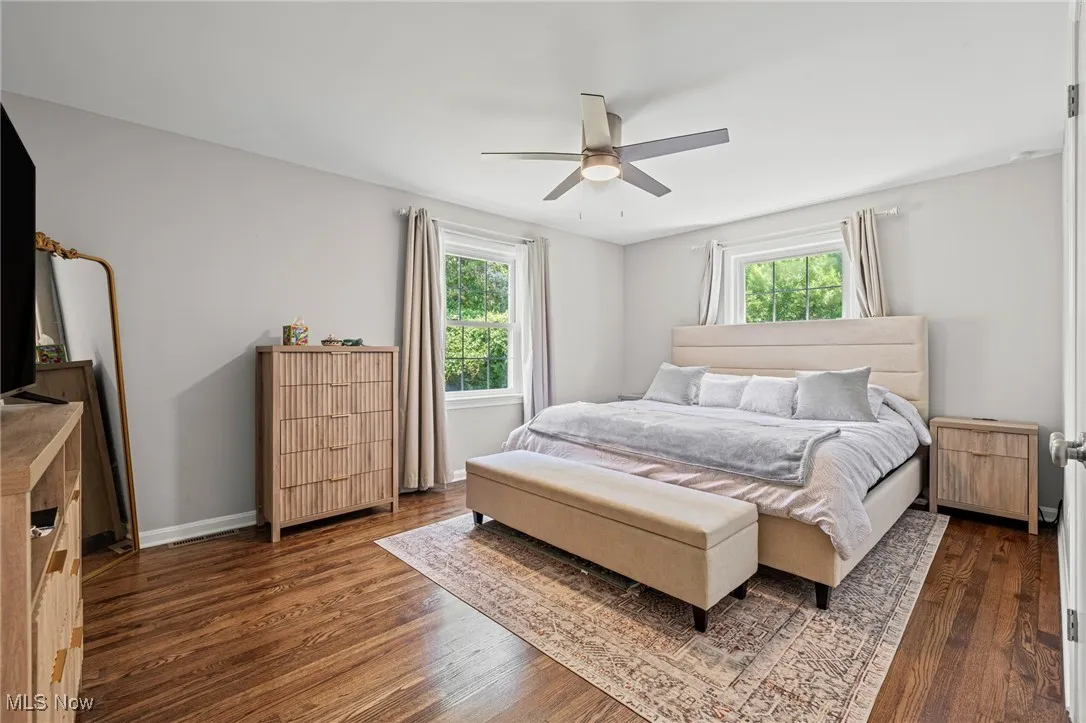 Bedroom featuring multiple windows, dark wood-style floors, and a ceiling fan