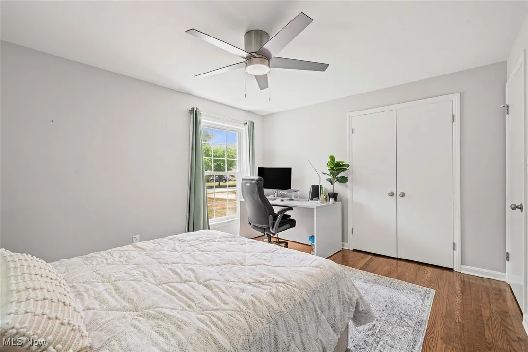 Bedroom with wood finished floors, a desk, ceiling fan, and a closet
