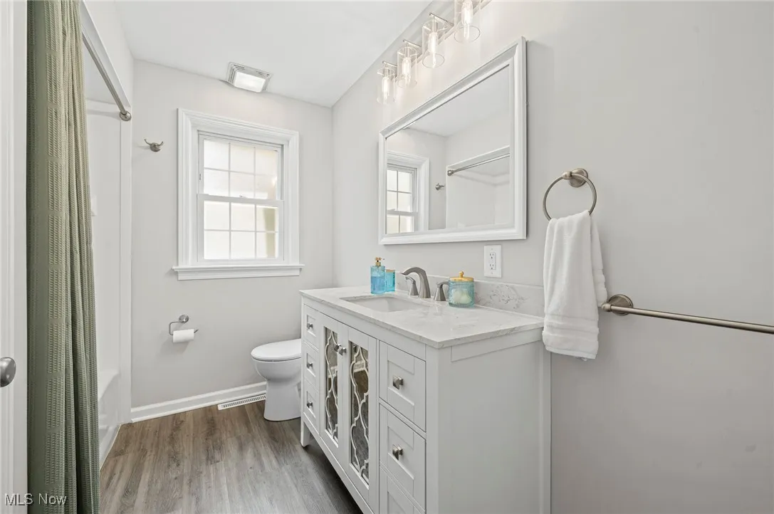 Full bath featuring vanity, wood finished floors, and shower / bathtub combination with curtain