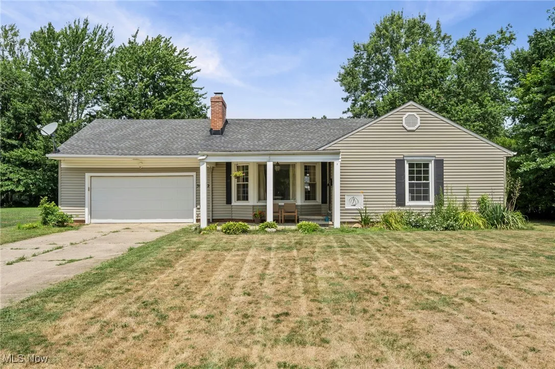 Ranch-style home with a garage, concrete driveway, a porch, a front yard, and roof with shingles