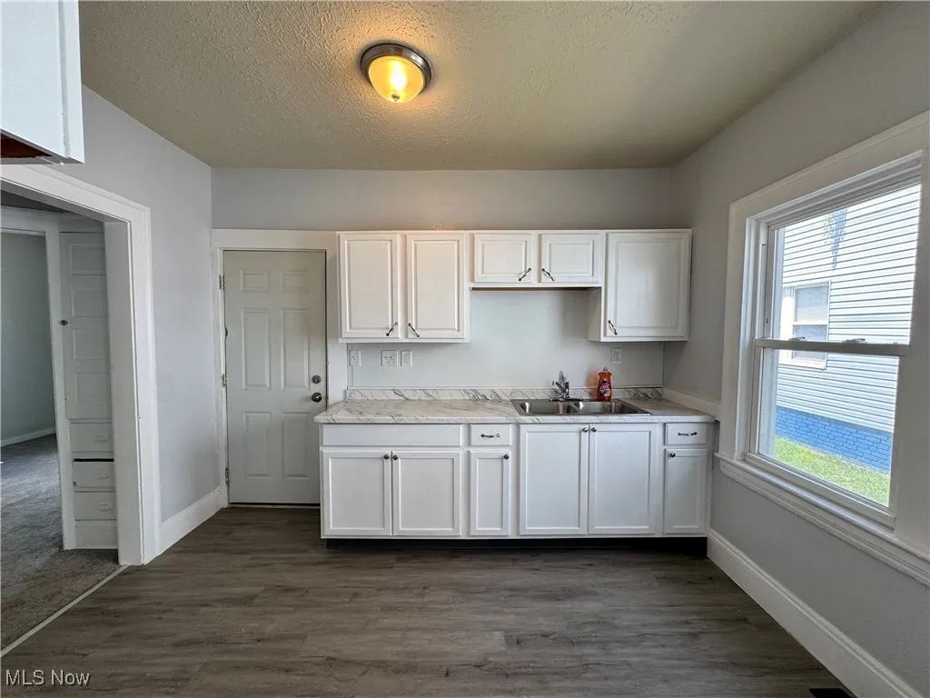 Kitchen featuring a textured ceiling, white cabinetry, dark wood finished floors, and light countertops